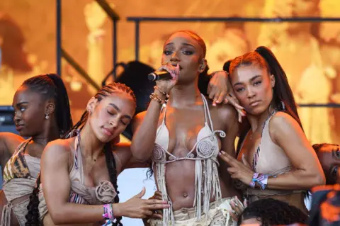 LEON NEAL/GETTY IMAGES Nigerian artist Ayra Starr (C) performs on the Pyramid Stage during day four of Glastonbury Festival 2024 at Worthy Farm, Pilton on June 29, 2024 in Glastonbury, England. 