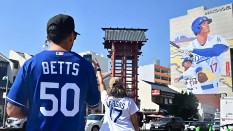 Getty Images Tourists pose for a photo in front of a massive mural of Shohei Ohtani in the Los Angeles neighbourhood of Little Tokyo 