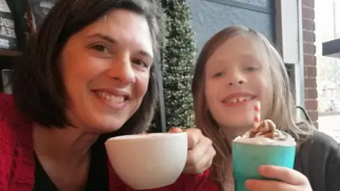 SUPPLIED Alex and her son Max who is nine years old sat in a coffee shop smiling and holding hot drinks. 