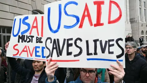 Getty Images People Protes Di luar markas untuk USAID sebelum Demokrat Kongres mengadakan konferensi pers di Washington DC pada 3 Februari 2025. Mereka memegang tanda -tanda yang mengatakan: "USAID harus diselamatkan" Dan "USAID menyelamatkan nyawa".