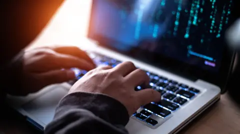 Getty Images Hands on a laptop which looks like a fraudster at work.