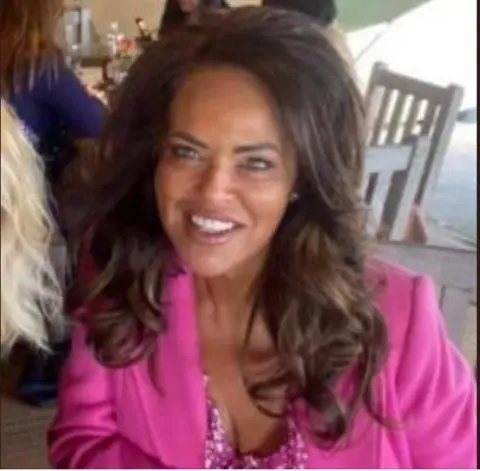 Facebook Janet Savage in a pink silk blouse, smiling at the camera