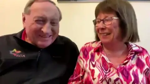 Colin and Bernie Wright left to right, Colin wears a black top and is smiling alongside Bernie who is wearing a pink and white swirly top.
