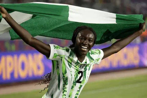 ABDEL MAJID BZIOUAT / AFP / GETTY IMAGES Nigeria midfielder Rinsola Babajide run across the pitch with the national flag after winning.
