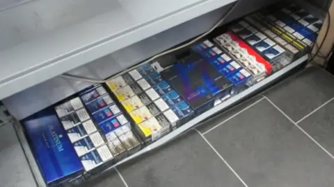 West Yorkshire Trading Standards Multi-coloured packets of cigarettes in a grey metal shop tray