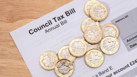 Council tax bill with pound coins on top