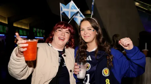 PA Media Two female Scotland fans at the Hydro. They have saltire deely boppers and are holding drinks.