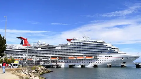 Getty Images Travellers trying to board the Carnival Panorama cruise ship for a 7 day trip were met with a delay in Long Beach, US.