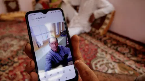 Mukhtar Zahoor Bhashir shows a picture of his brother, Fayaz, who was killed by alleged militants in Pulwama.