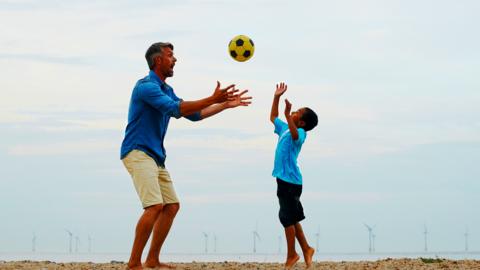 A man and a boy playing with a football