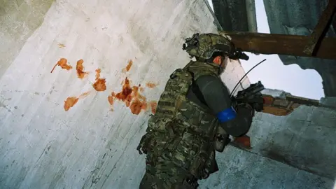 Conall Kearney A soldier aims a gun next to a blood-splattered wall