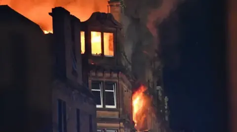 Stuart Cowper Fire rips through the upper floors of a tenement block at night