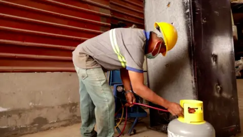 A worker at Angel's plant extracts refrigerant gases from an old fridge