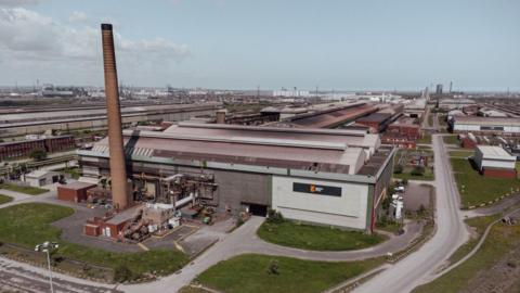 The British Steel site, large concrete buildings with a tall brick chimney.