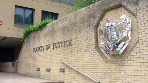 Colin Smith Steps beside a brick wall lead to the main entrance of Southampton Crown Court. On the wall is a large silver emblem and the words "Courts of Justice".