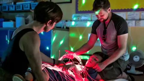 Gympanzees Young person exploring fibre optics with parents