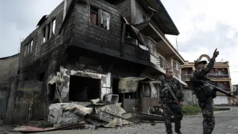 Getty Images Police inspect damaged buildings in Marawi, Mindanao. Photo: 29 May 2017