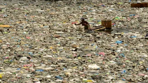 Getty Images A scavenger wades through garbage in Manila, 2016