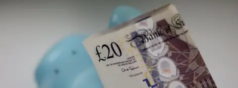 PA Twenty pound note in a piggy bank
