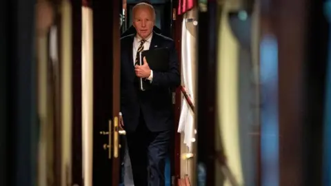 Reuters President Joe Biden walks down a corridor to his cabin on a train after a surprise visit with Ukrainian President Volodymyr Zelenskiy