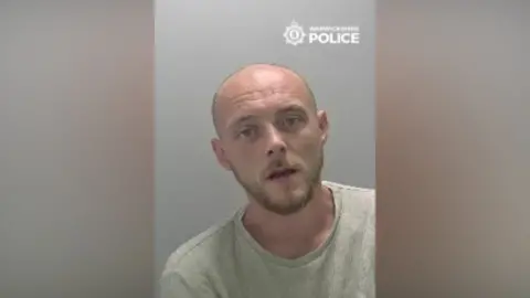 A police mugshot of a man wearing a t-shirt.