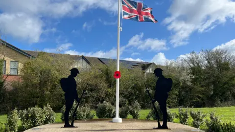 BBC Two silhouettes of soldiers with a white pole with a poppy and a British flag on it