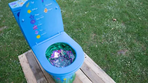 A closer look at the blue toilet, which is patterned with flowers on the inner lid and inside the bowl.