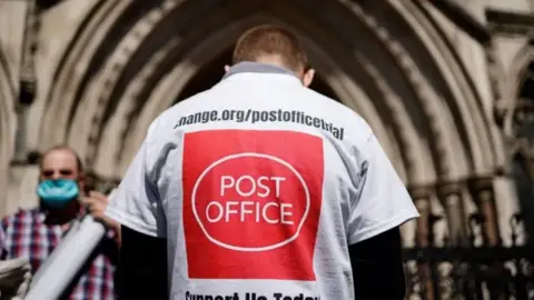 Getty Images A campaigner outside court from behind, wearing a t-shirt emblazoned with a Post Office logo and slogan