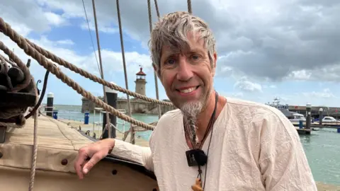 Chrissie Reidy/BBC A man in a white top on a boat.