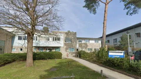 Google The mental health unit, with a blue and white sign outside that says "Chalkhill", and grass and trees outside.