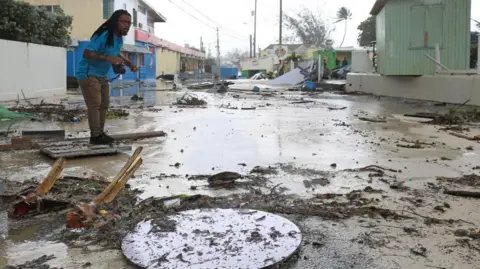 Reuters A man walks along a debris-filled street in the Hastings neighborhood after Hurricane Beryl passed in Bridgetown, Barbados July 1, 2024.