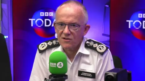 Sir Mark Rowley speaks into a green mic in the BBC Radio 4 studio