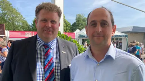 BBC/Cara Thorpe Farmers William Maughan and Richard Pears stand side-by-side at the Great Yorkshire Show. Mr Maughan wears a navy jacket, blue checked top and a blue and red striped tie. Mr Pears wears a light blue shirt.