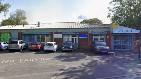 A nursery building with a small car park in front of it.