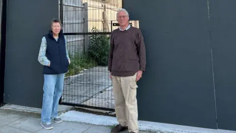 Chapel Green Association A man in a woman stand next to a boarded up area