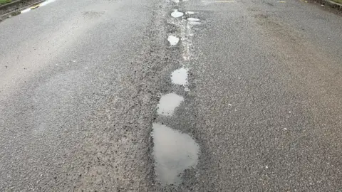 A row of potholes down the middle of a road 