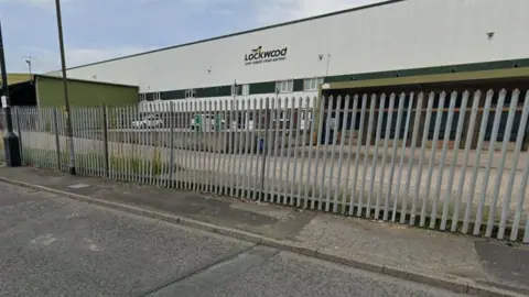 The front of a premises behind a metal fence on an industrial estate. The name 'Lockwood' is emblazoned across the front.