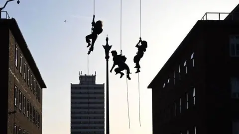 Getty Images The silhouettes of three people abseiling in Coventry 