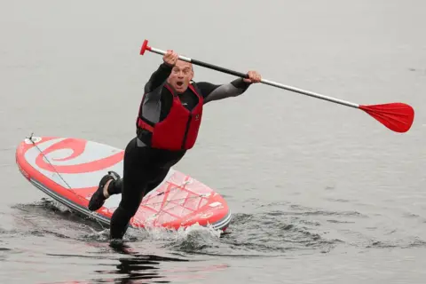 Phil Noble/REUTERS British leader of the Liberal Democrats party Ed Davey falls from a paddle board, at Lake Windermere in Windermere, Britain, 28 May 2024