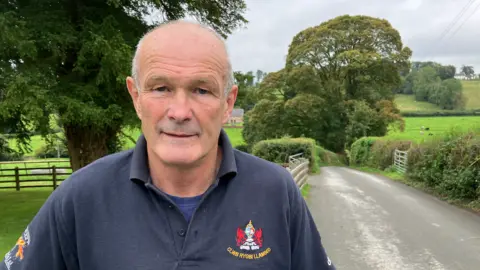 Dai Charles Evans, wearing a dark blue polo shirt, standing in a country lane