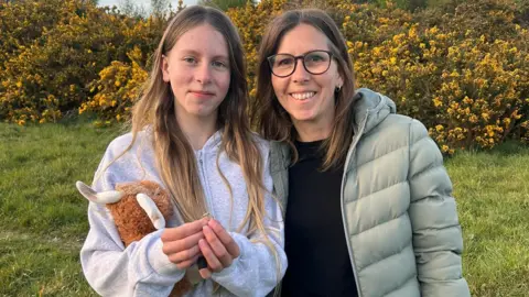 Maxine (right) and her daughter Poppy (left) holding a ring while standing in a garden