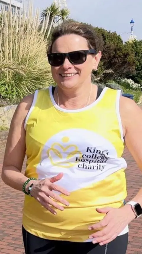 A woman in a yellow vest running on a promenade
