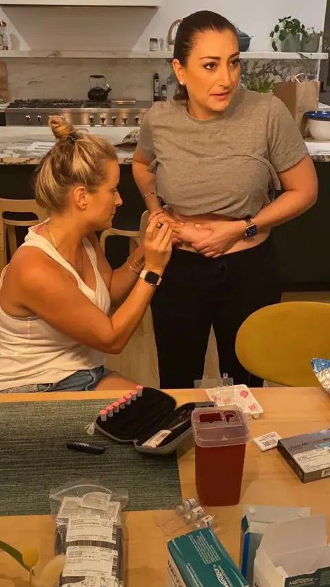 Supplied by Sara Jacobs Congresswoman Sara Jacobs injects herself with the help of a friend