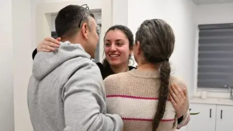 Israeli Army Karina Ariev smiles as she hugs a man and a woman