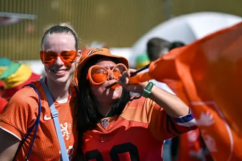 Getty Images Two Dutch fans party in the streets of Lucerne wearing bright orange clothes and oversized sunglasses