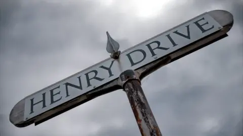 BBC The Henry Drive sign beneath a moody grey sky