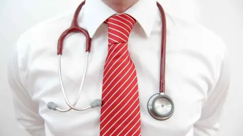 A model posing with a stethoscope around his neck