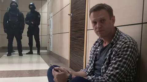 Reuters Alexei Navalny sits on the floor outside the office of his Anti-Corruption Foundation during a police raid in Moscow, 26 December 2019