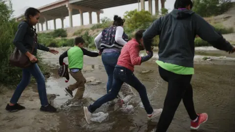 Getty Images Migrants enter Texas through the US-Mexico border