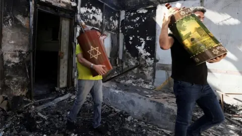 Reuters Torah scrolls, Jewish holy scriptures, are removed from a synagogue in the city of Lod, Israel (May 12, 2021)